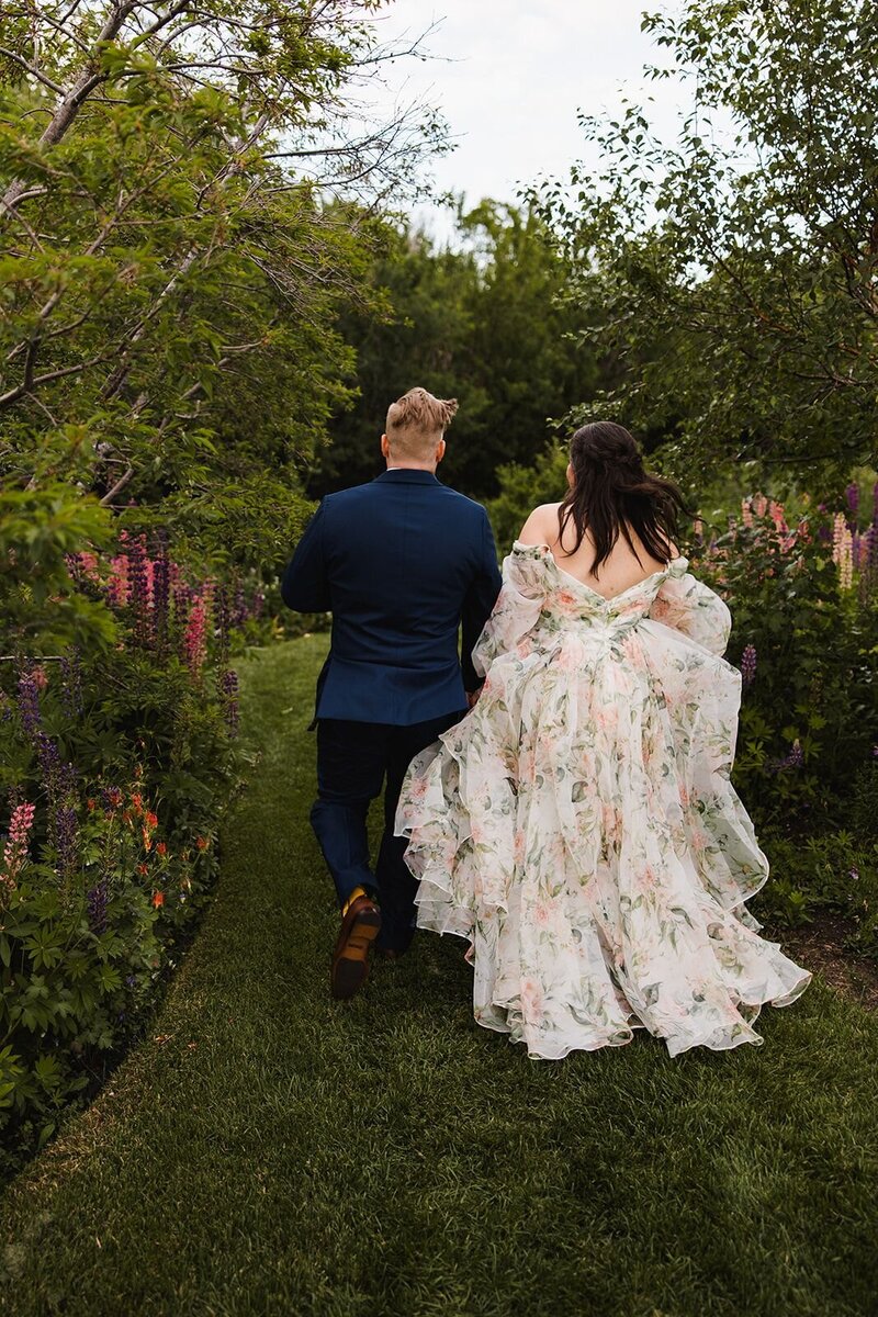 Couple running through the garden with their backs towards the camera