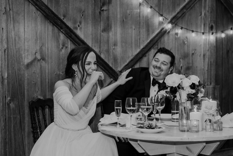 A newlywed couple laughing and sitting at a table together