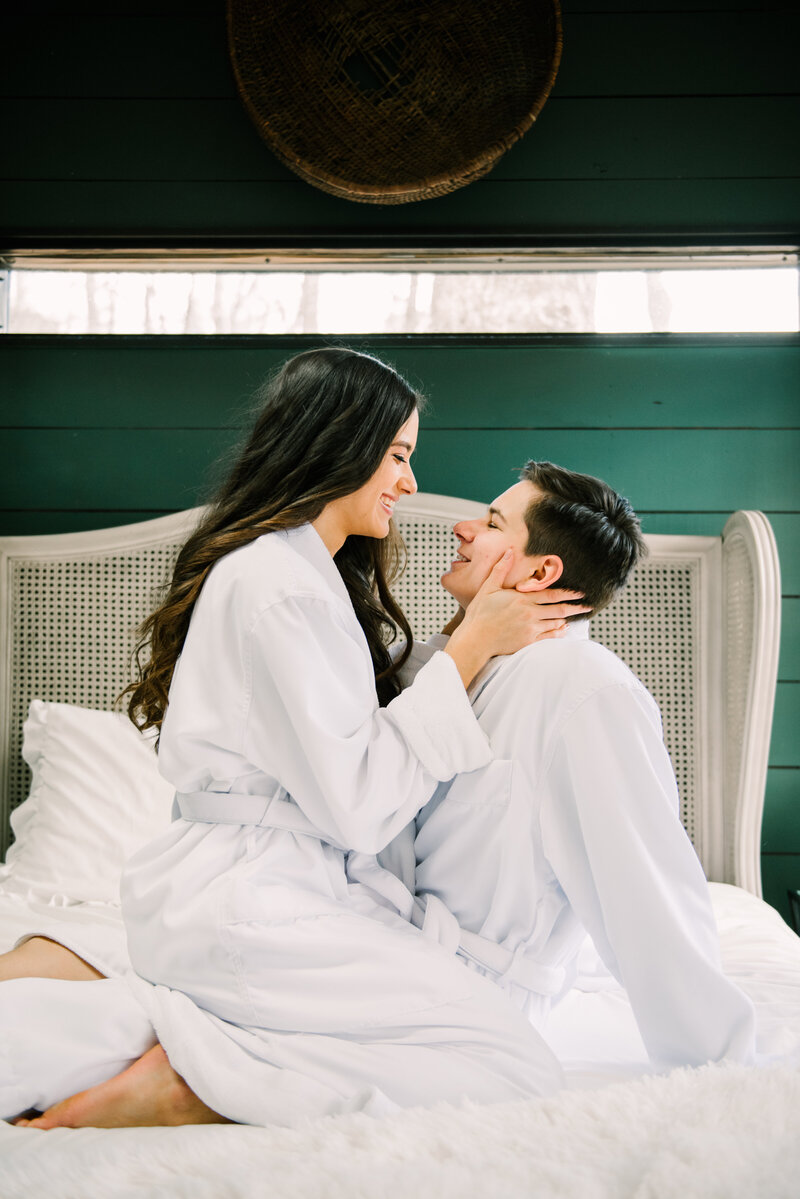 Couple embraces in bed before treehouse elopement.
