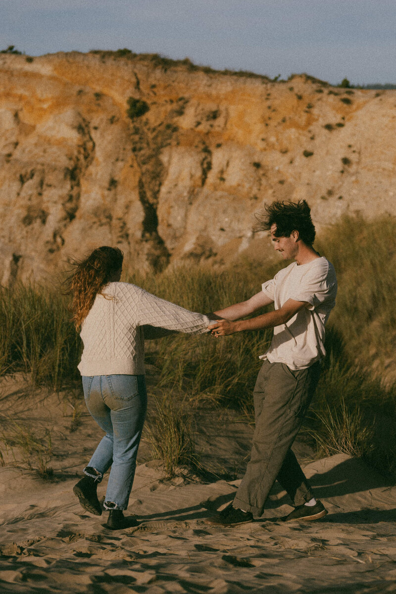 A couple laughing as they hold hands and spin in a circle 