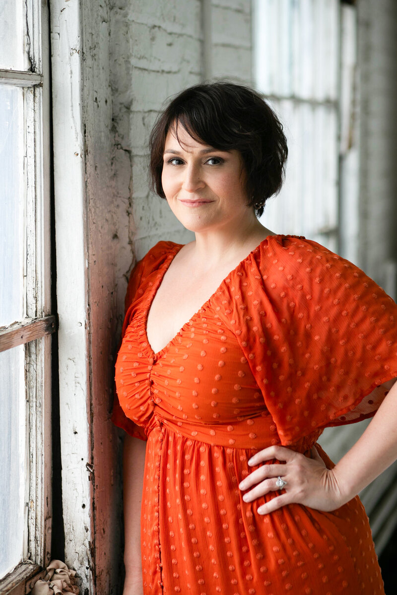 A woman smiling with one hand on her hip
