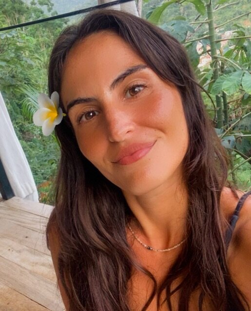 Brenda Ramirez smiling with a plumeria flower in her hair at a tropical wellness retreat in Mexico.