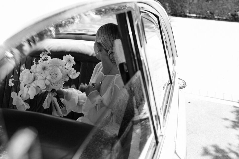 a bride arrives at her wedding ceremony at the rose historic chapel in an old white car