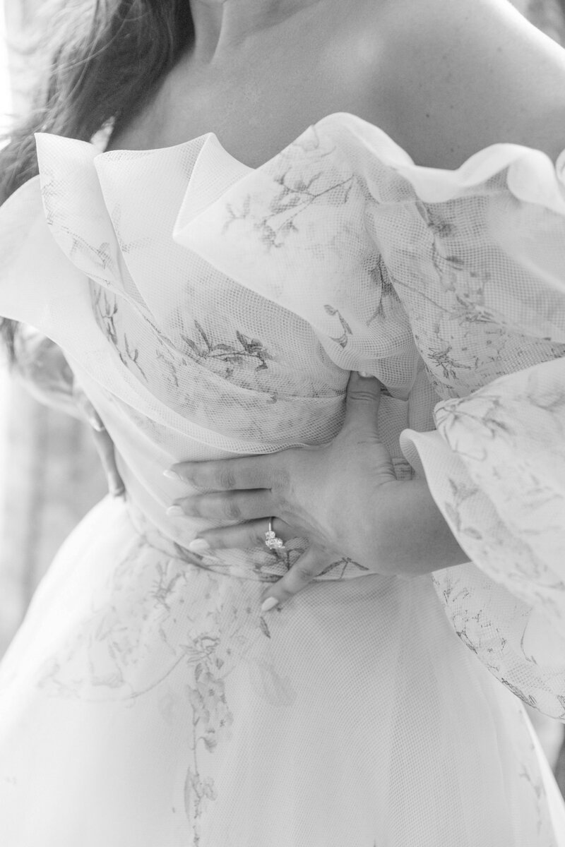 black and white photo of bride putting on her monique lhuillier wedding dress