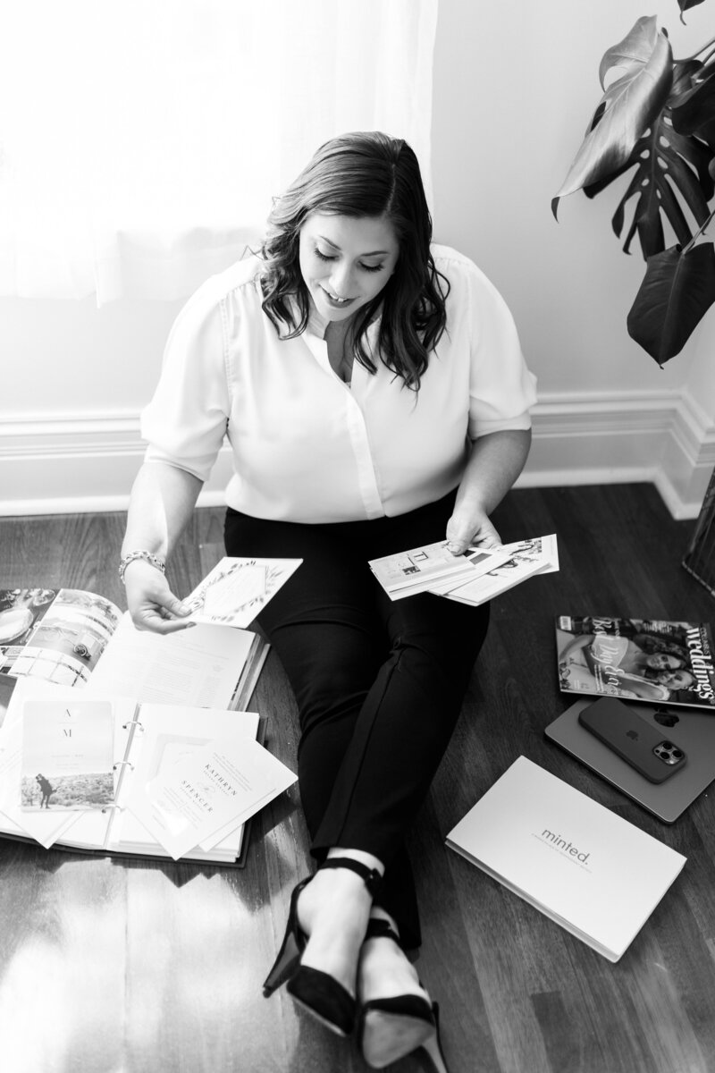 Wedding planner sitting and reviewing color swatches and wedding magazines, thoughtfully curating the perfect details for a couple's special day in Columbus, OH.