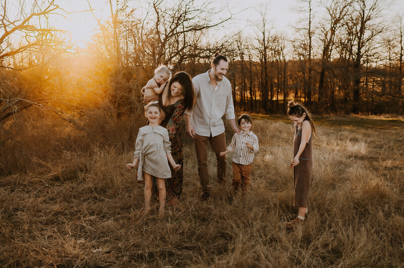 A family of 6 walking in a field smiling and laughing at Murrell park In Flower Mound, Texas