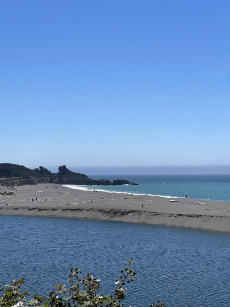 large body of water with people walking on the shore