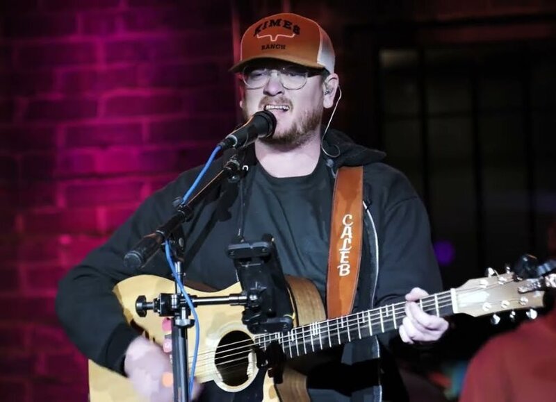 A person playing guitar and singing on a stage 