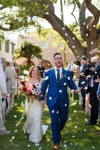 Newlyweds walking down aisle as guests toss flower petals at outdoor St Augustine wedding ceremony captured by professional wedding photographer