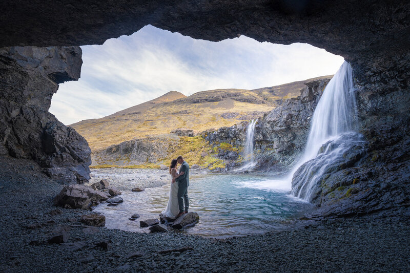A couple in their wedding attired are kissing while standing on the basalt columns of the black sand beach Reynisfjara in Iceland.