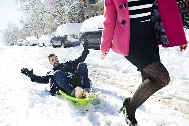 A person pulling their partner across the snow on a sled 