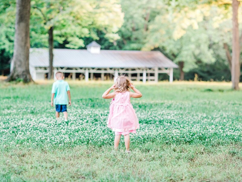 children in white clover field by white barn