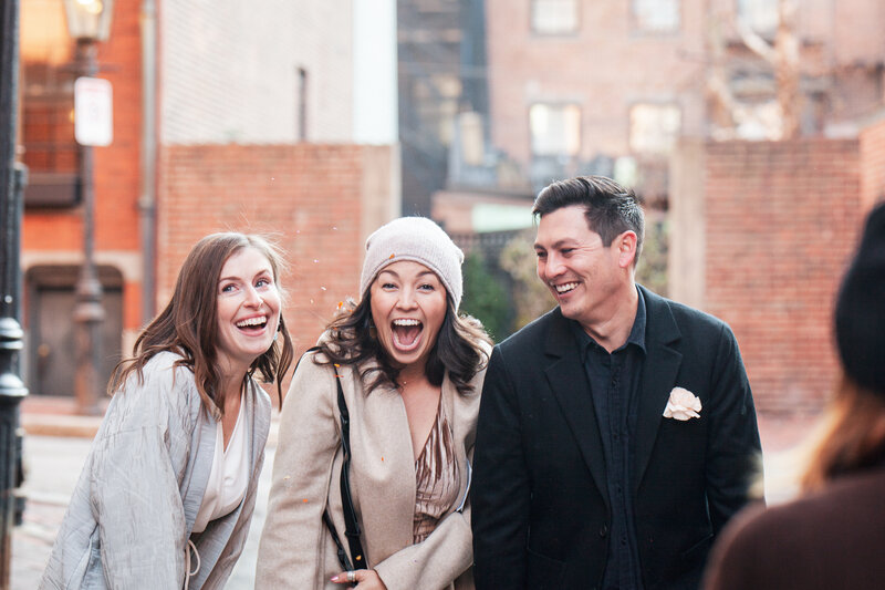 Sam smiles widely at the camera with confetti in the air after a city elopement in Boston
