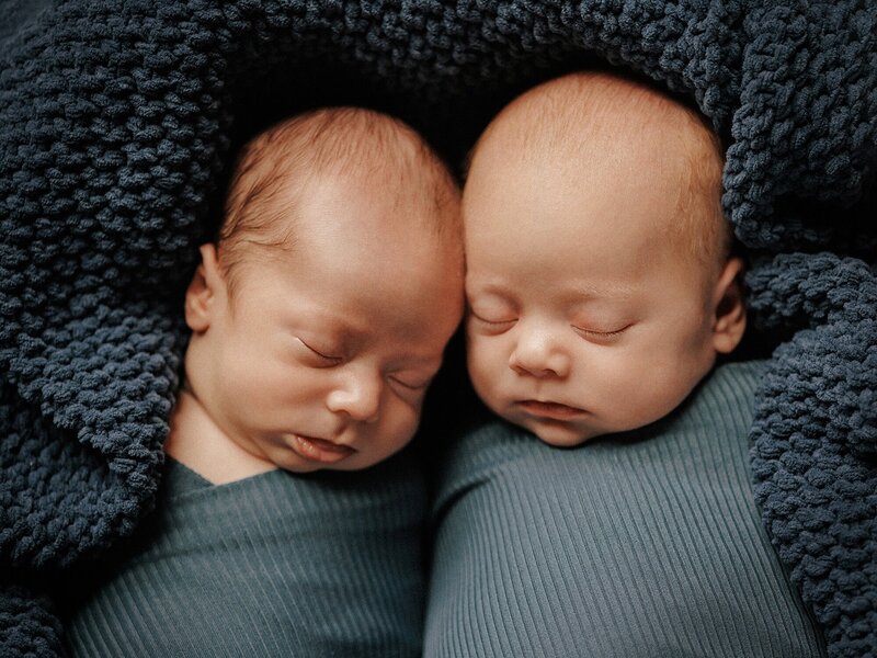 Newborn babies sleeping in a basket during photography session