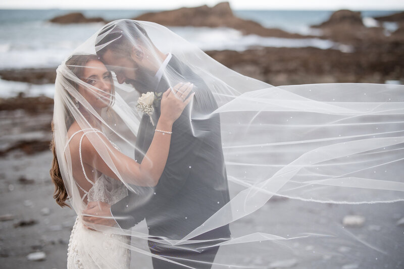 Bride and Groom under the veil on their wedding day at Tunnels Beaches wedding in Devon