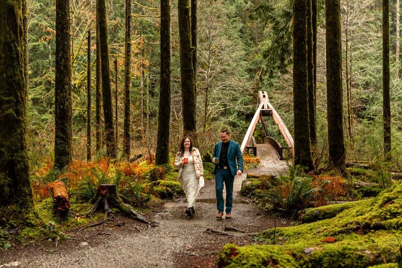 Couple walking in the forest with mugs and green moss