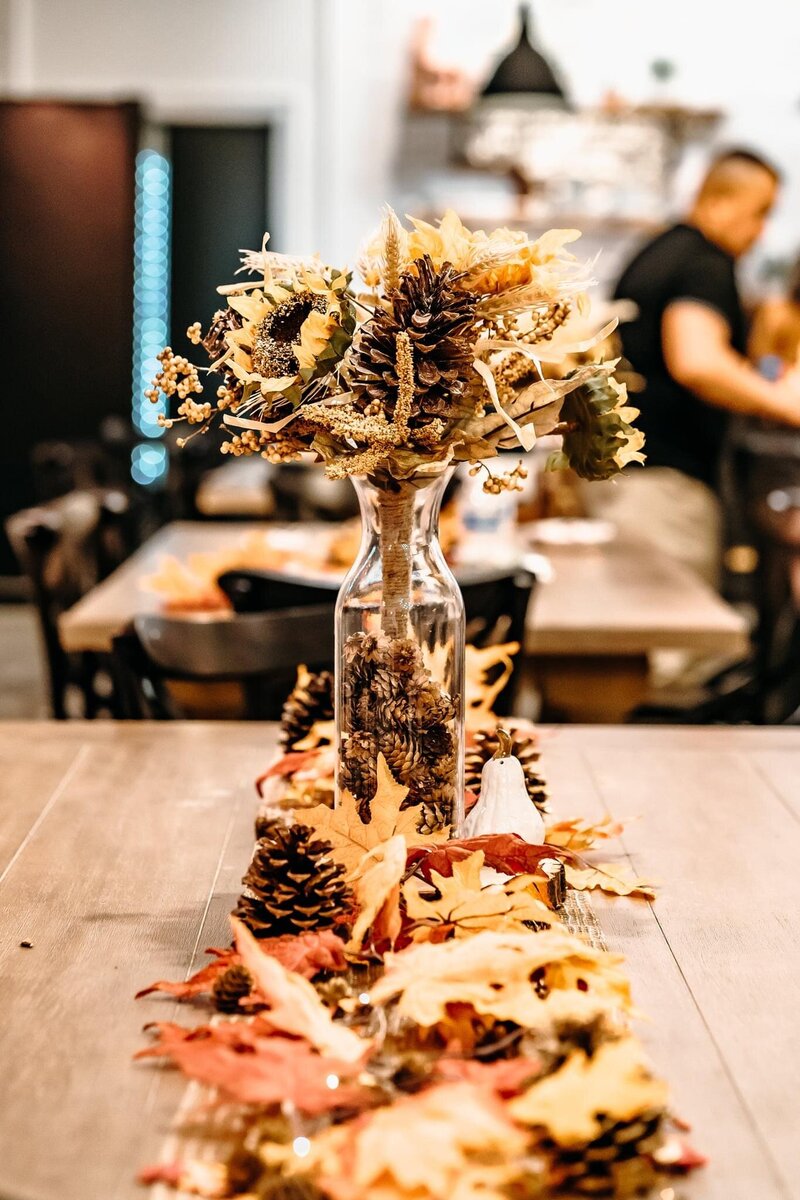 A decorated table with fall decor and a centerpiece.