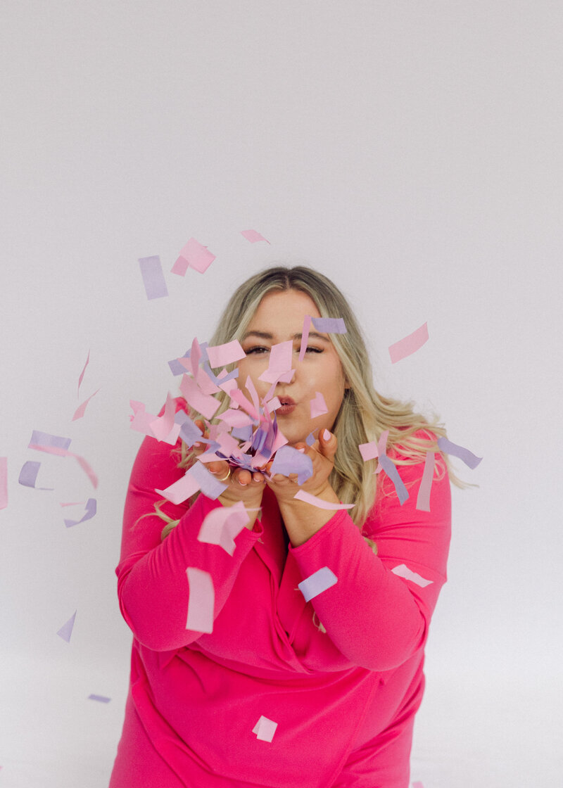 Happy business women blowing confetti