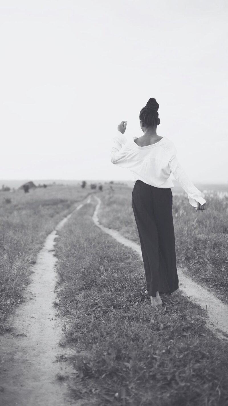 Black woman walking through an open field, symbolizing clarity and forward movement in leadership and life transitions.