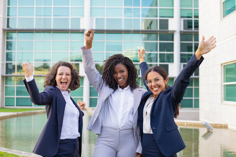 3 women in business suites making a yes expression with their hands