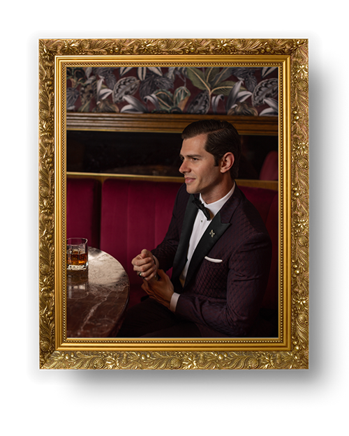 Editorial-style portrait of a man in a tuxedo in a red velvet booth. Photographed by Heist Creative for a fashion campaign in Sydney.
