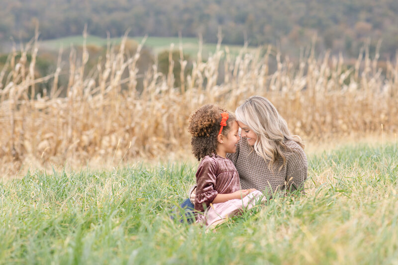 biracial mother and daughter sit together in a field