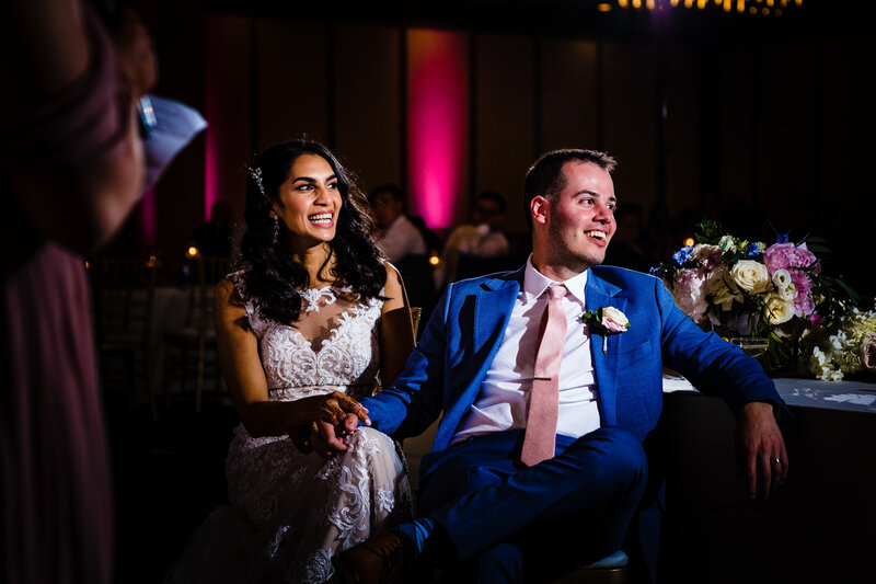 Wedding couple sitting and laughing during the toast of the best man during the reception at the Renaissance Hotel in Toledo Ohio