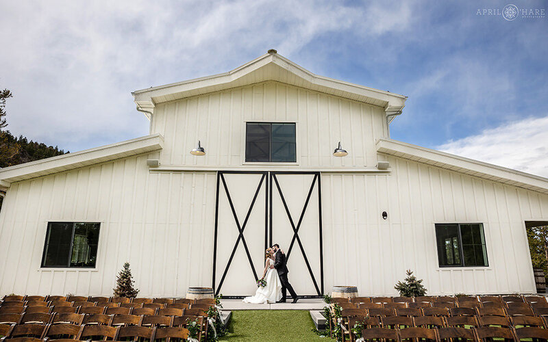 Couple stands outside of the White Barn at The Woodlands in Colorado