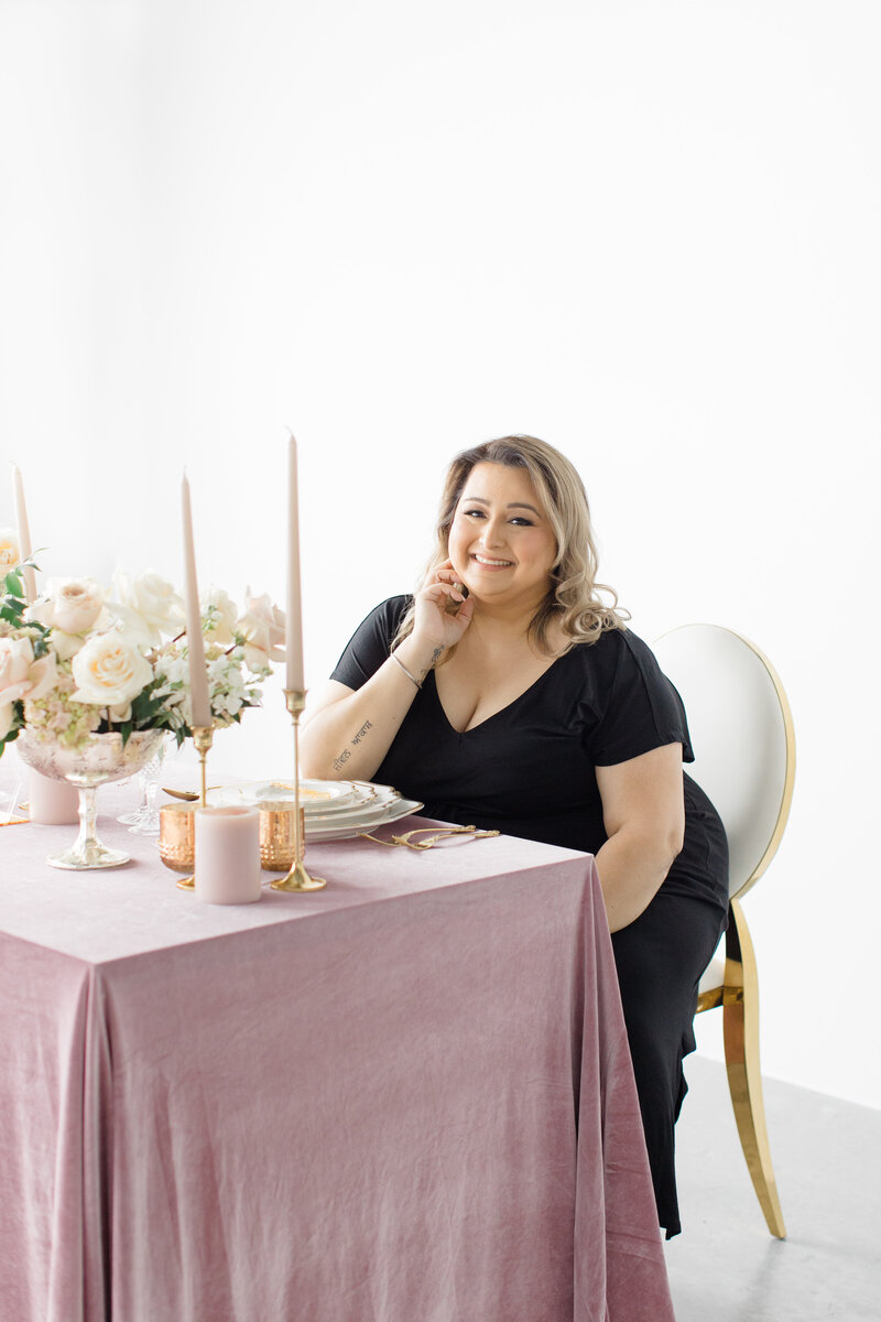 wedding planner smiling in front of a decorated wedding table with a pink table cloth
