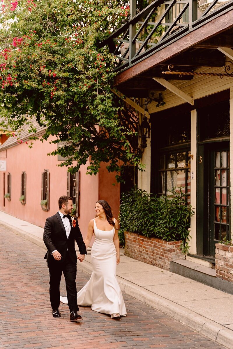 Bride in simple white gown and groom in black soon walking hand-in-hand