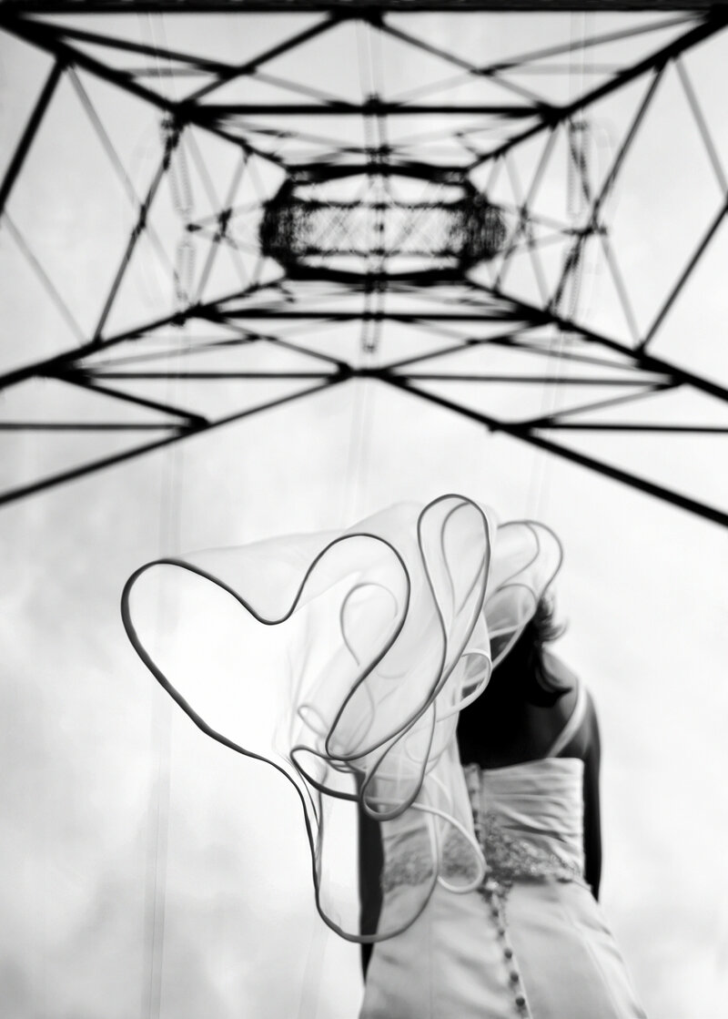Looking up at a veil as the bride stands under a power line tower.
