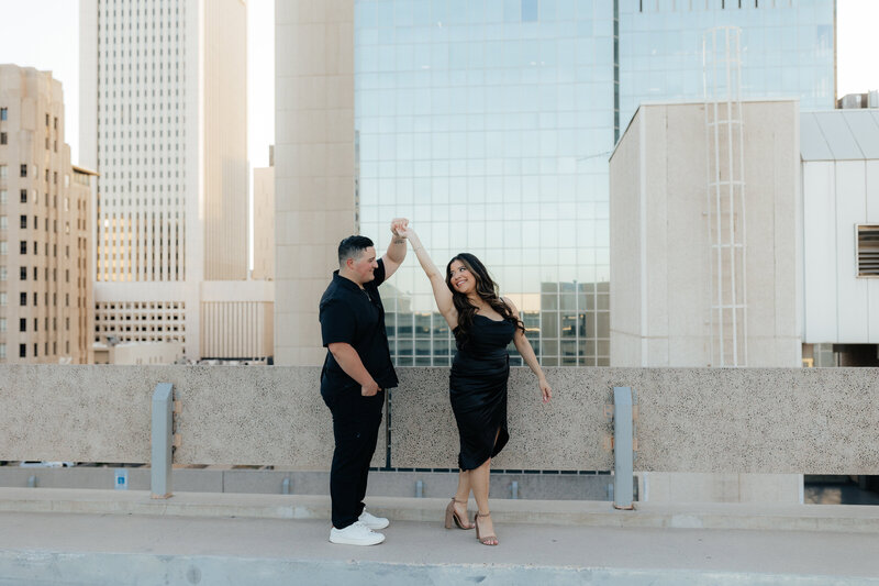 man spins a women during their engagement session in downtown Phoenix