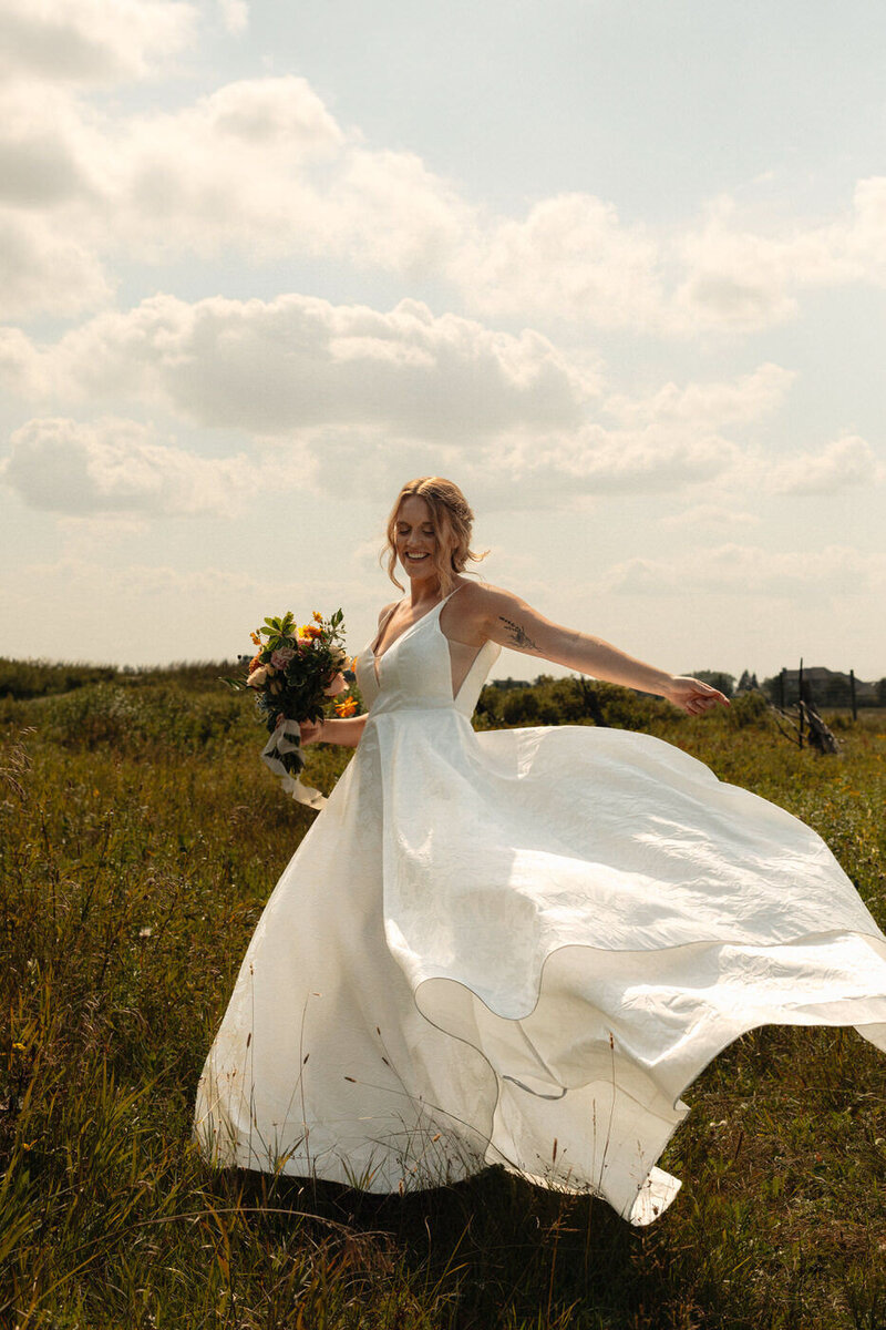 Bride twirling in the summer field at Fort Whyte 
