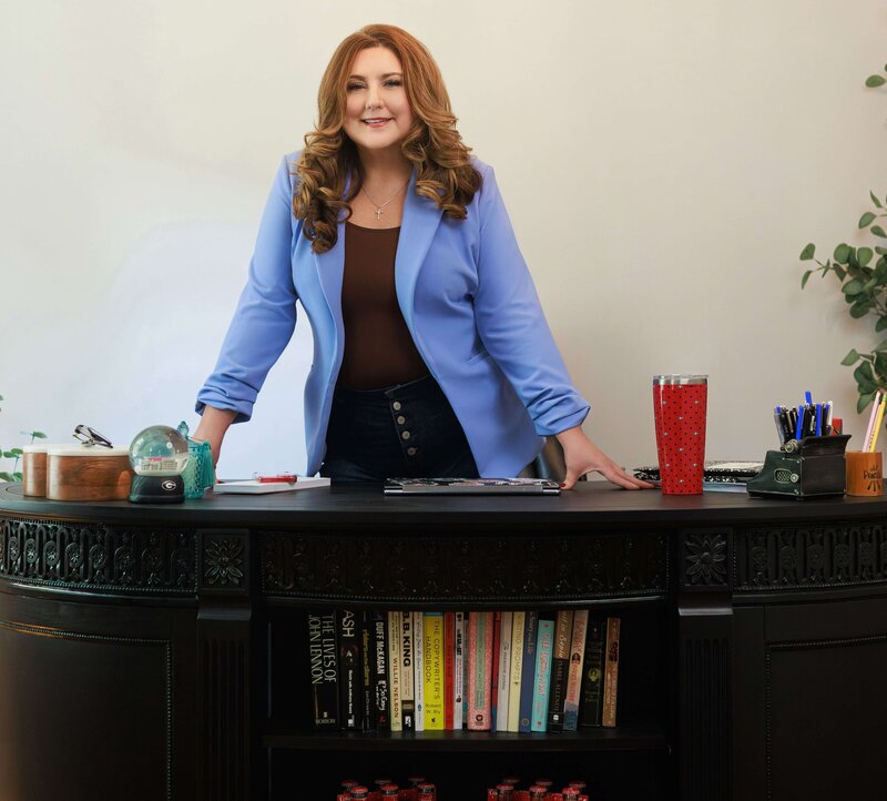 woman in a blue blazer standing behind a black desk