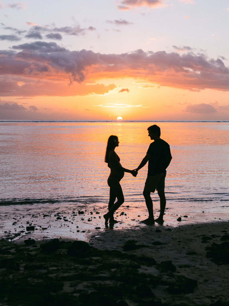 Couple souriant portrait plein pied sur les rochers a la plage pendant la grossesse