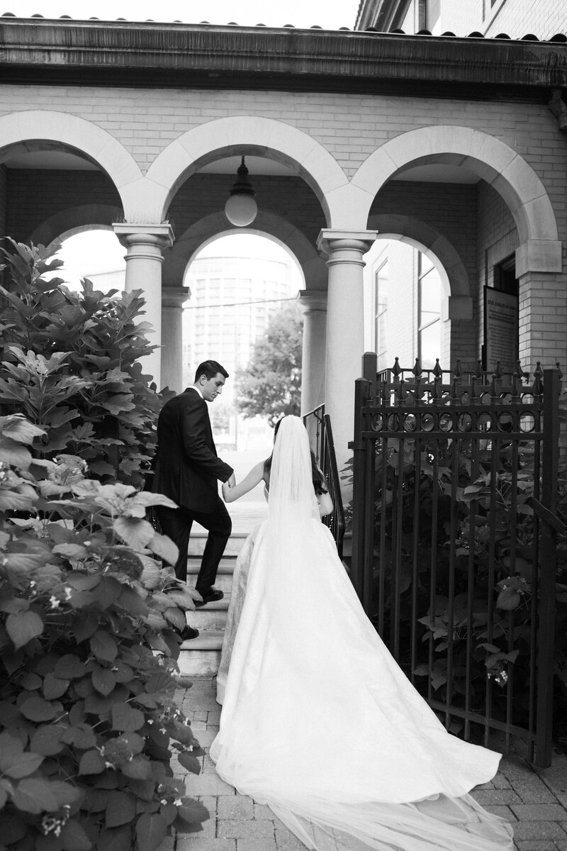 A bride and a groom holding hands smiling walking out of their cathedral wedding venue in Nashville, Tennessee.
