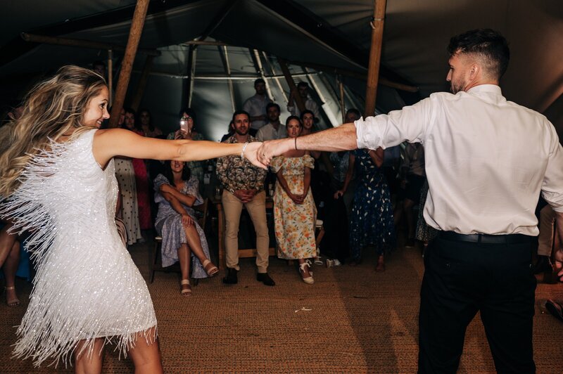 bride in mini beaded white reception dress dances with groom in elements tipi at their christchurch wedding