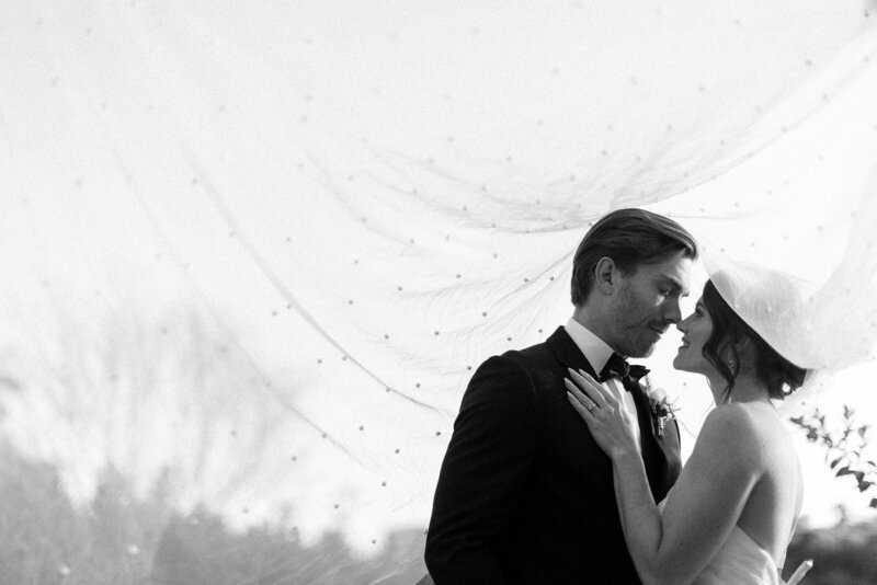 Wedding photographer in Houston captures a bride and groom under a veil in black and white.