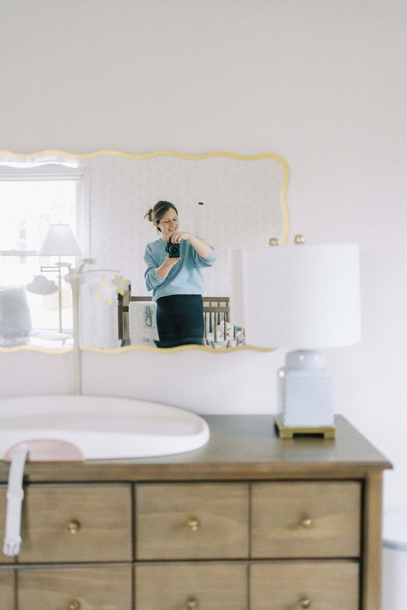 photographer taking photo of herself in the mirror at newborn photo session