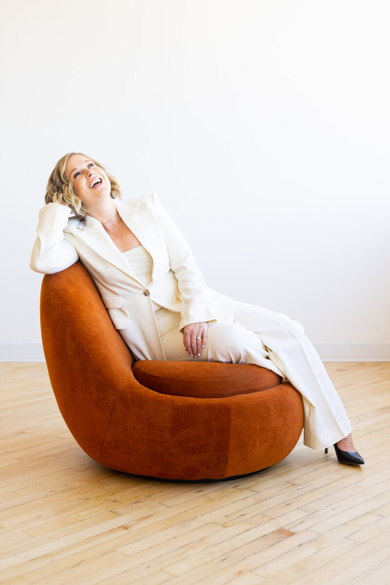 Girls Club Collective founder Lis Best laughing on an orange chair