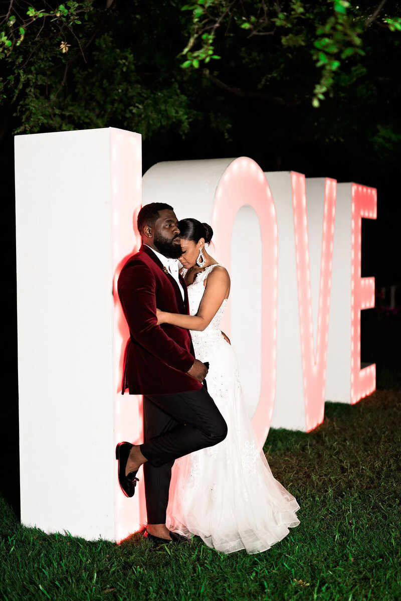 Swank Soiree Dallas Wedding Planner Kerri and Bravion at the Dallas Arboretum and Botanical Garden - Bride and Groom in front of a love sign