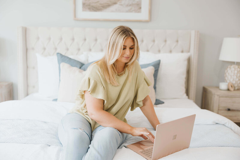 Jacie Dykes, Raleigh Realtor looking at laptop on bed in raleigh home.