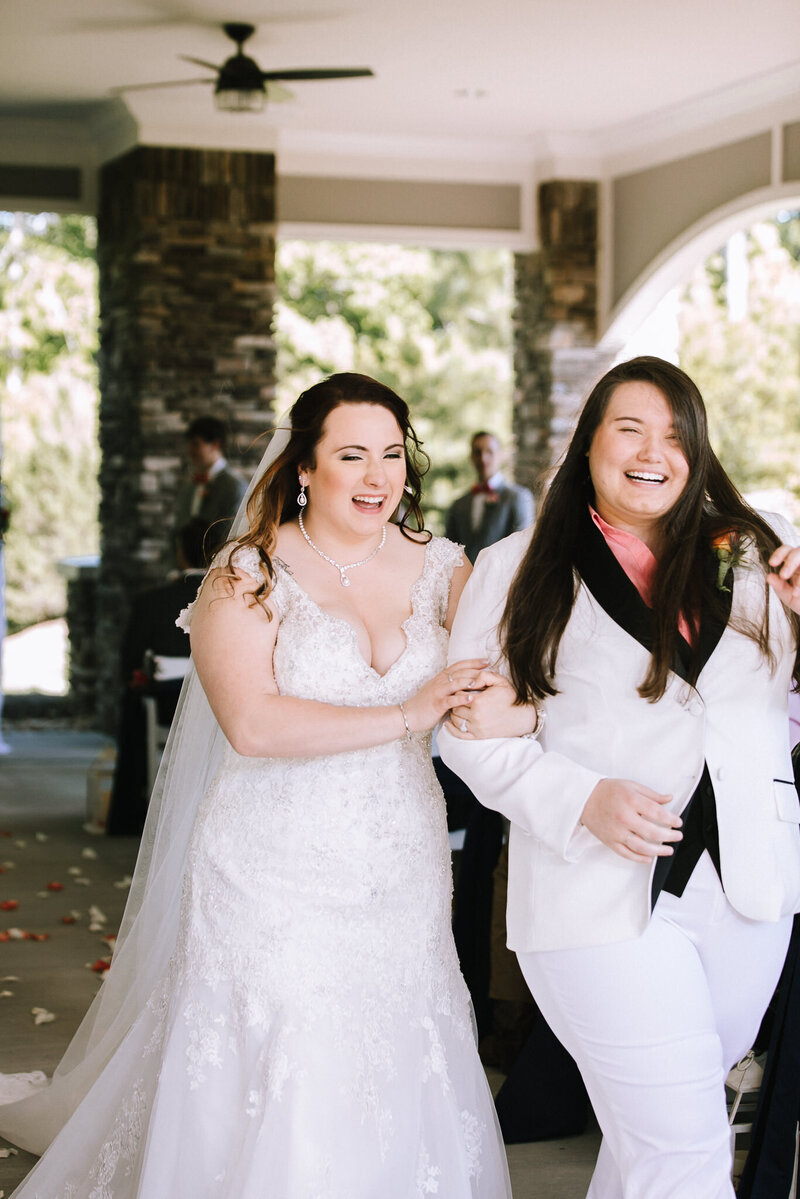 Two brides walk down the aisle after being married at Southern Charm Events in Rock Hill, SC as their Rock Hill wedding photographer photographs them.