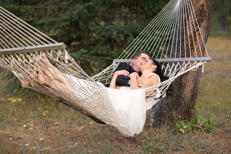Bride and Groom snuggled in a hammaock hanging in the woods.