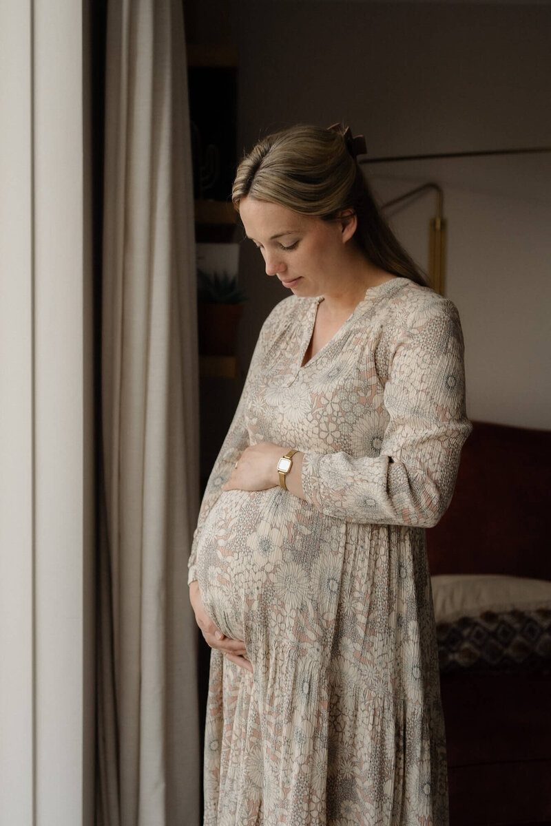 zwangere vrouw kijkt naar buik tijdens zwangerschapsshoot, gefotografeerd door familiefotograaf Julia de Groot