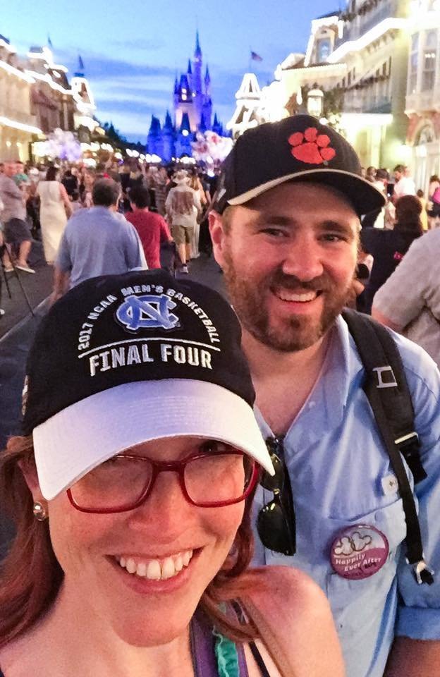 NC wedding photographer Elyssa Kivus snaps a selfie with husband John at Disney World; she's wearing a UNC championship hat and he's wearing a Clemson championship hat
