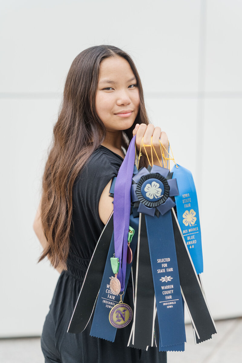a high school senior holding several ribbons and awards medals