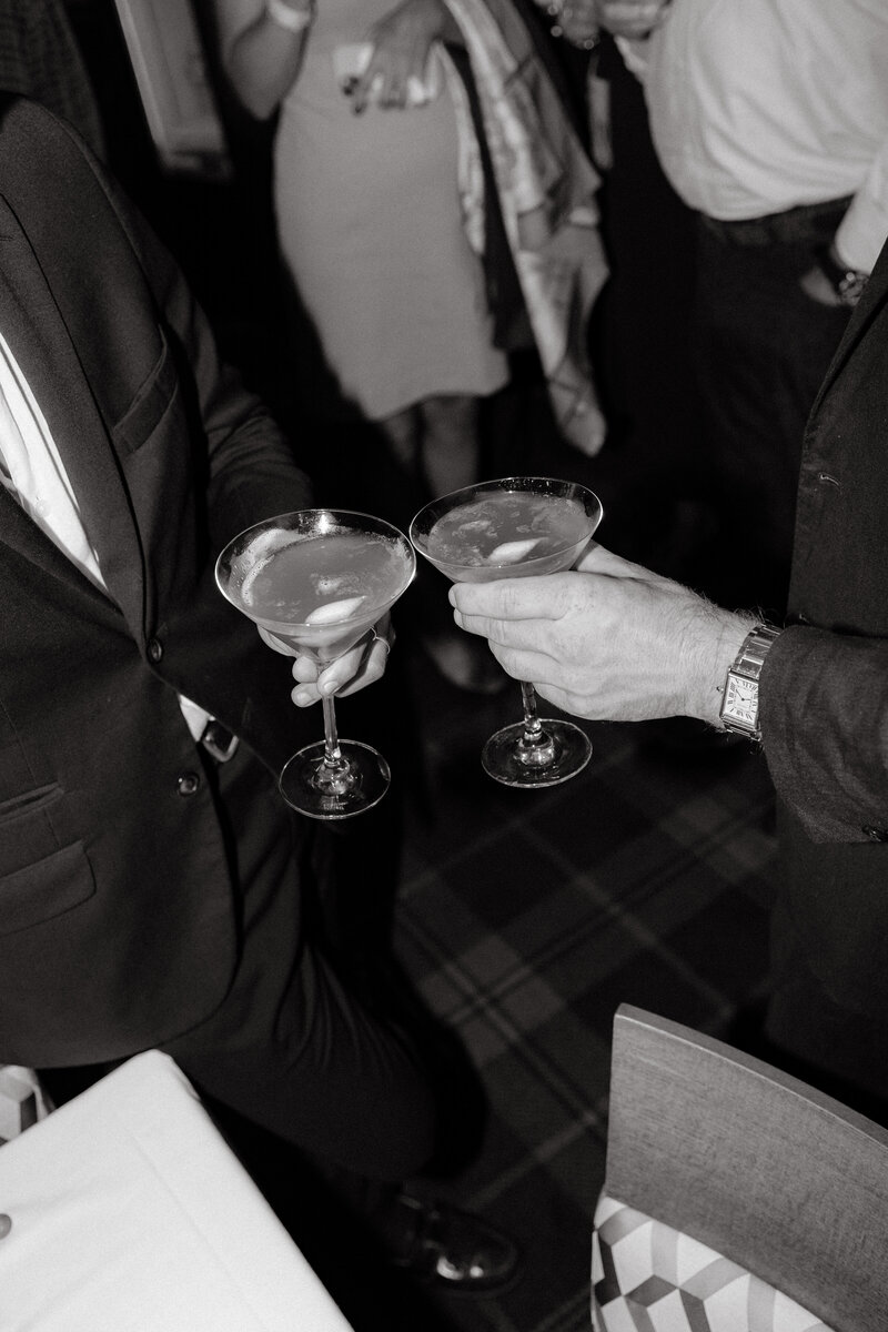 Two men holding martinis at a wedding reception