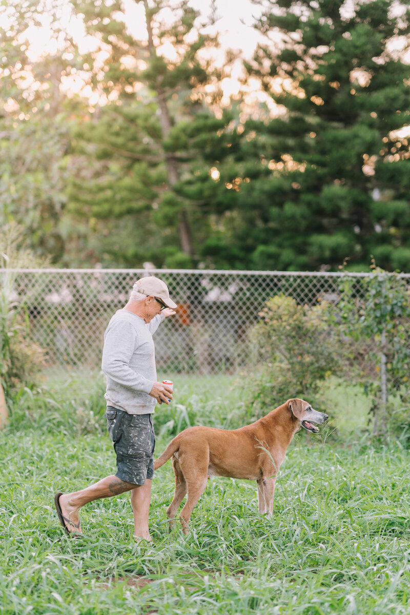 a man walks with his coffee and his dog in a golden lit park in Portland, Oregon