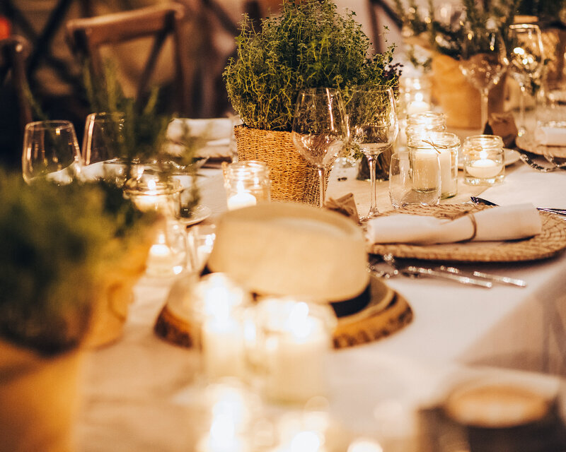 A wedding or event table is set with rustic baskets with herbs.